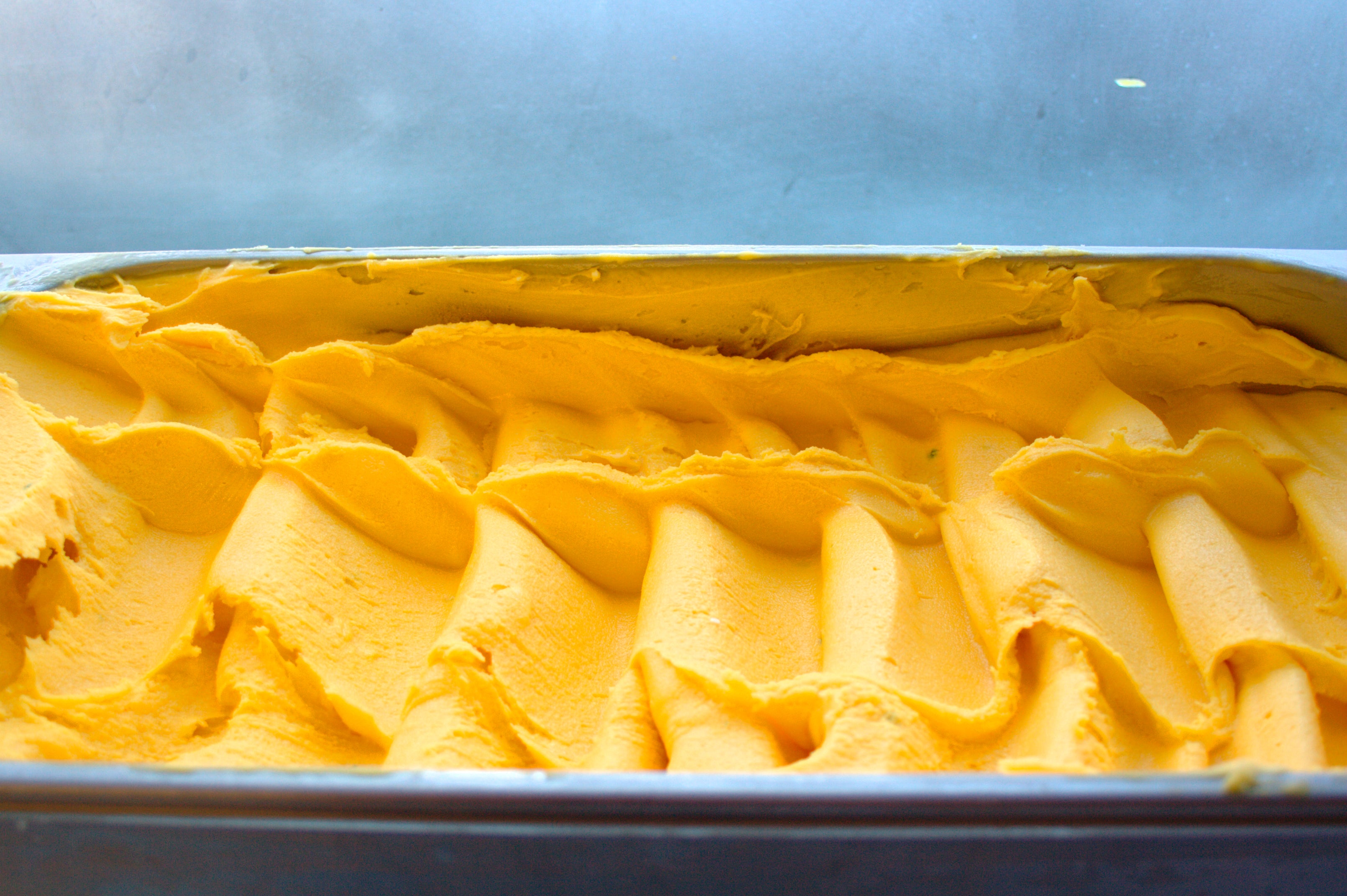 Mango sorbetto in a metal container on a gray background