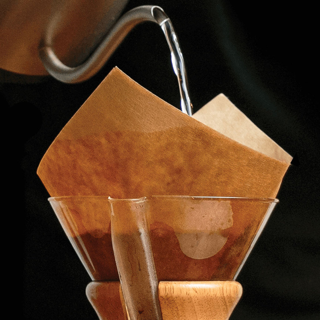 Coffee being poured into a paper filter with a dark background