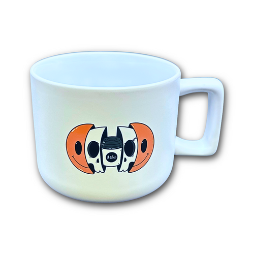 White mug with a cartoon design of a coffee cup layered inside a skull that is layered inside an orange smiley face