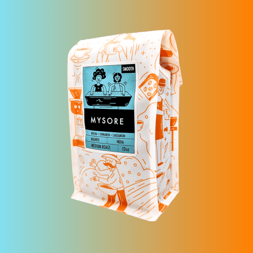 Angled view of a 12oz Bibo Coffee Co. bag showing a light blue label for 'Mysore' medium roast coffee from India, noting a smooth profile, washed process, and tasting notes of mocha, cinnamon, and cardamom.